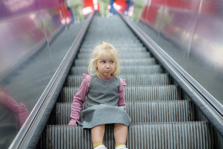 A little girl on the stairs of an empty escalator in the subway.の写真素材