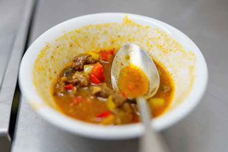 Unfinished soup in a plate with a spoon on the table.の写真素材