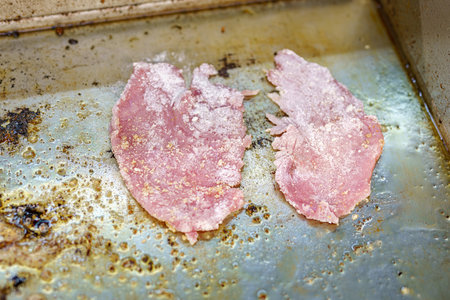 Frying a pork chop on the stove in a restaurant kitchen.の写真素材