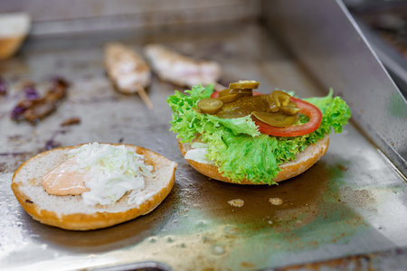 Cooking a bacon burger and cutlet with salad and cheese in a restaurant.の写真素材