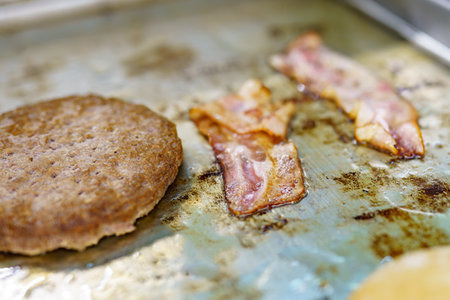 Fried bacon and cutlets for making a burger with cheese and vegetables.の写真素材