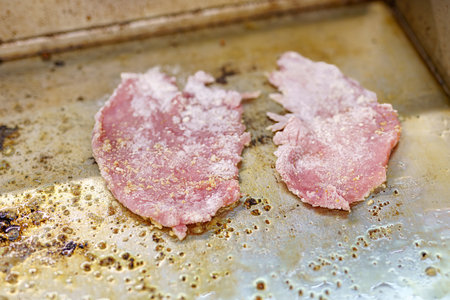 Frying a pork chop on the stove in a restaurant kitchen.の写真素材