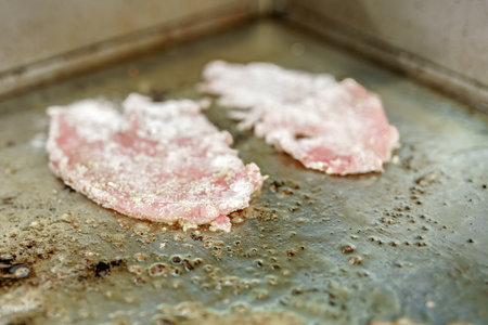 Frying a pork chop on the stove in a restaurant kitchen.の写真素材