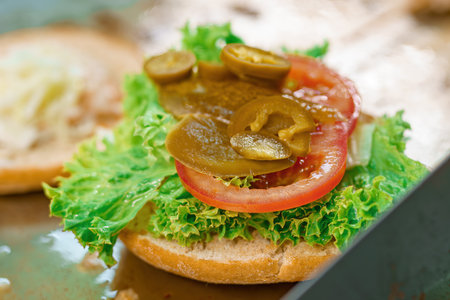 Cooking a bacon burger and cutlet with salad and cheese in a restaurant.の写真素材