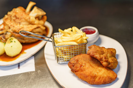 A dish of meat in dough with French fries on the background of a dish of pork knuckle in a restaurant.の写真素材