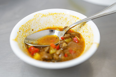 Unfinished soup in a plate with a spoon on the table.の写真素材