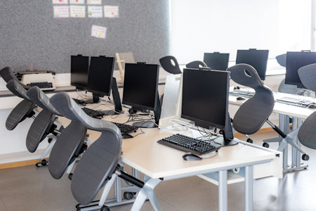 Monitors and keyboard in an empty computer lab at a secondary school.