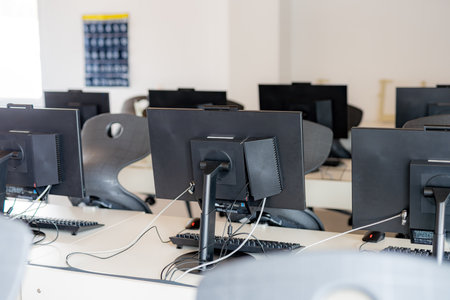 Monitors and keyboard in an empty computer lab at a secondary school.