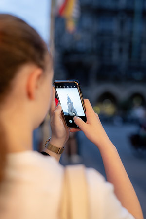 A girl takes pictures of the Catholic Church on a smartphone in the evening.