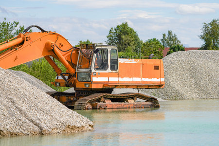 An excavator stands in the water at a quarry during a flood.