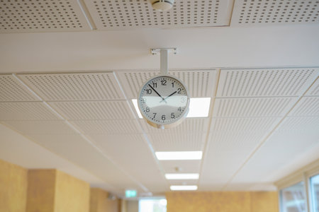 A clock above the ceiling in the hallway of an office building.の写真素材