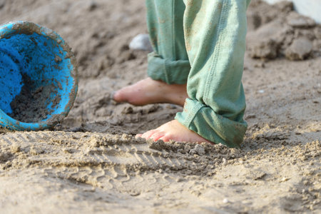 The child plays in the sand and walks barefoot.の写真素材