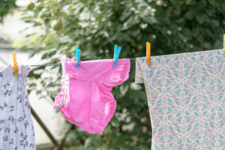 A woman hangs baby laundry to dry outside. Clean laundry after washing.の写真素材