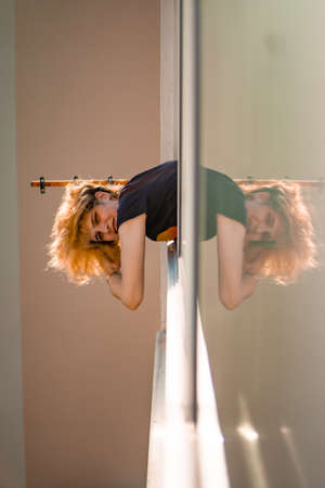 Blonde girl in window in quarantine reflected while corona virus pandemic