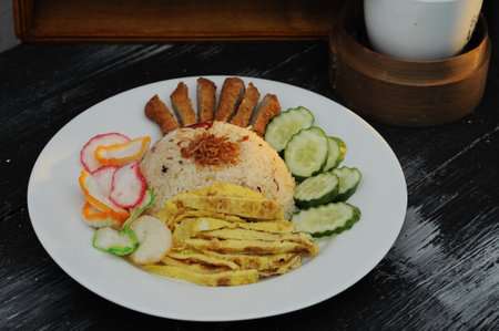 fried rice with nuggets, fried eggs and slice cucumber on white plateの写真素材