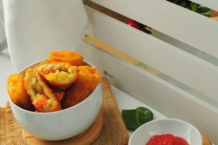 Deep fried crab stick in white bowl with tomato sauce on wooden tableの写真素材