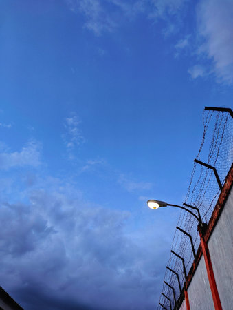 lights on a high railing against a backdrop of clouds at duskの写真素材