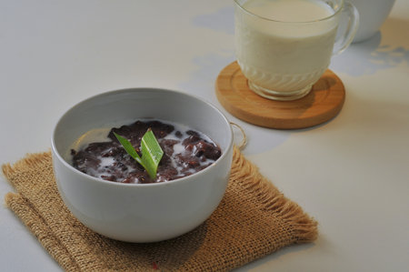 Black Glutinous Rice Porridge or Bubur Pulut Hitam in Malay with coconut milk on white backgroundの写真素材