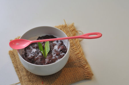Black Glutinous Rice Porridge or Bubur Pulut Hitam in Malay with coconut milk on white backgroundの写真素材