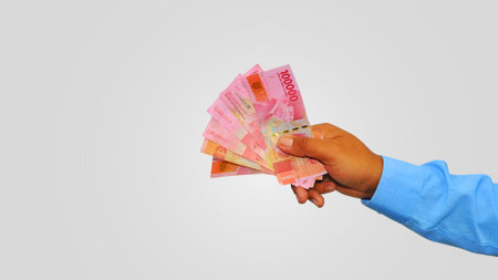 Hand holding indonesian currency rupiah on white background with copy space for text