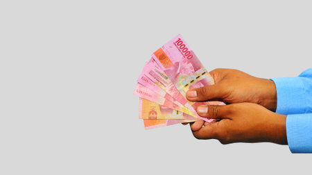 Hand holding indonesian currency rupiah on white background with copy space for text