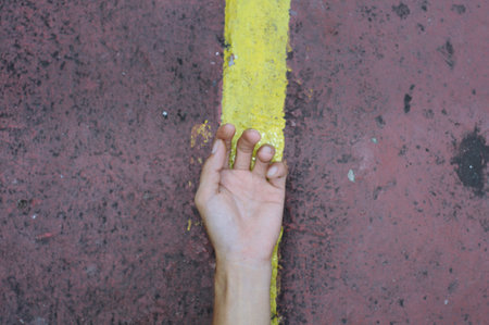 Close up of man hand holding yellow line on the road, selective focusの写真素材