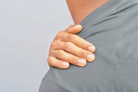 Man suffering from back pain on a gray background. Close-up.の写真素材