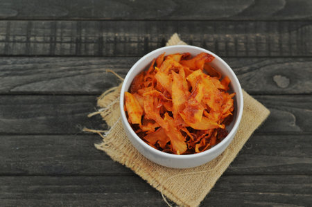Carrot chips in a bowl on a wooden table, top viewの写真素材
