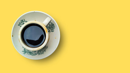 Cup of coffee on yellow background. Top view. Copy space.の写真素材