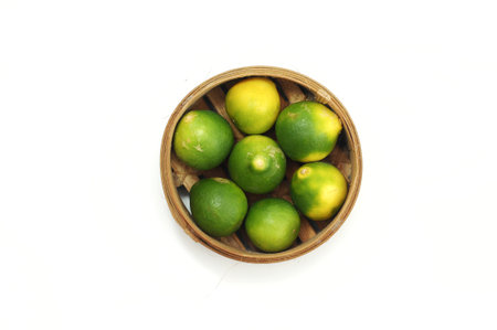 Limes in a wooden basket on a white background, isolate.