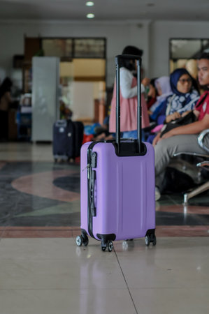 Purple suitcase in the airport waiting for boarding with people in background