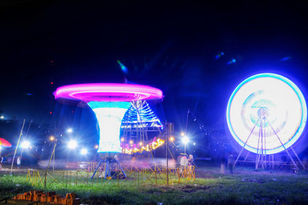 Unidentified people on the background of an amusement park at nightの写真素材
