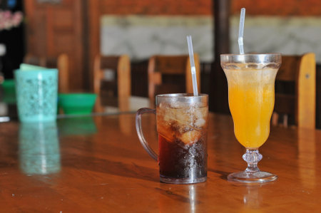 Iced coffee and orange juice in a glass on the table.の写真素材