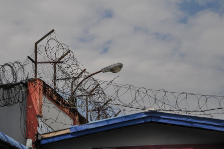 Barbed wire on the roof of a building with blue sky.の写真素材
