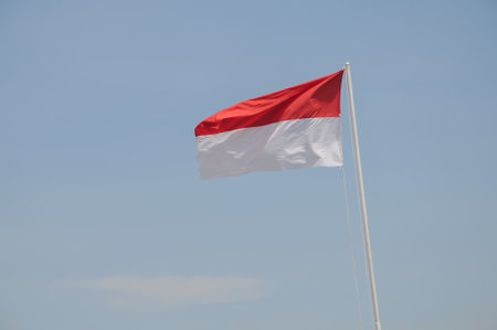 Indonesian flag waving in the wind on blue sky background.の写真素材
