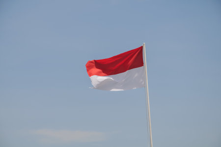 Indonesian flag waving in the wind against the blue sky.の写真素材