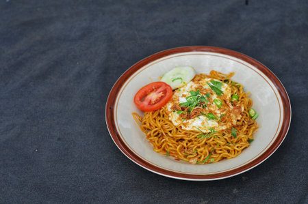 fried instant noodle with egg and vegetable on black table background.の写真素材
