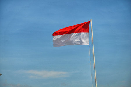 Indonesian flag waving in the wind against the blue sky.の写真素材