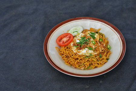 Fried instant noodle with egg and tomato on black background.の写真素材
