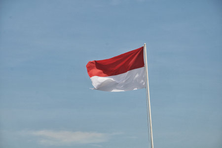 Indonesian flag waving in the wind with blue sky background.の写真素材