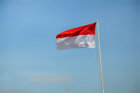 Indonesian flag waving in the wind on blue sky background.の写真素材