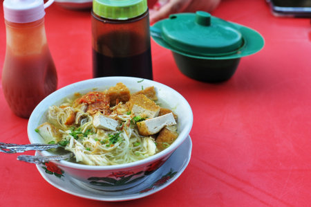 Noodle soup with pork in bowl on red table, Thailand.の写真素材