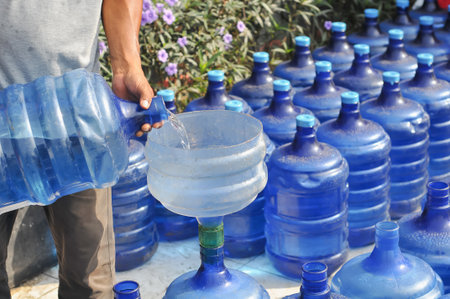 Man pouring water from plastic bottle into plastic container, closeup of photoの写真素材