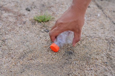 Plastic bottle in hand on the beach. Plastic waste concept.の写真素材