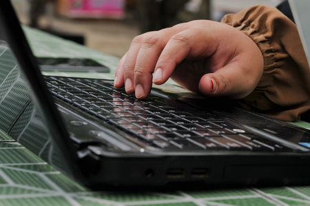Close-up of a woman's hand typing on a laptop keyboardの写真素材