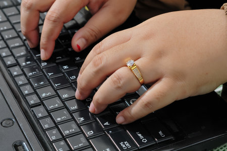 Woman typing on a laptop keyboard. Close-up of female hands.の写真素材