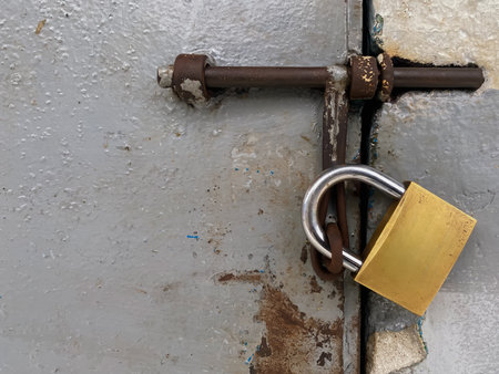 Old rusty padlock on a steel door with peeling paint.の写真素材