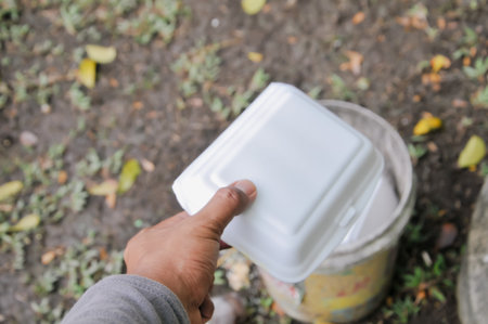 A man's hand is holding a white plastic container for food.の写真素材