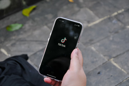 Woman hand holding Apple iPhone X with TikTok application on the screen. TikTok is a popular social networking service.の写真素材