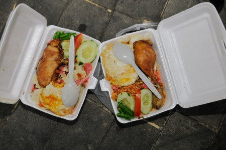 Grilled chicken with rice and fried egg in a plastic box.の写真素材